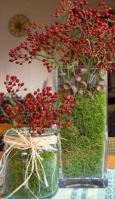 two vases filled with plants and moss on top of a cloth covered tablecloth