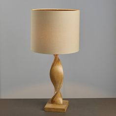 a wooden table lamp with a beige shade on it's base and a white lampshade