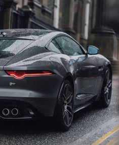 a grey sports car driving down the street in the rain