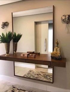 a large mirror sitting on top of a wooden shelf next to a vase filled with flowers