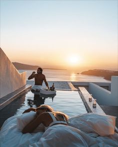 a man sitting on top of a bed next to a woman in a swimming pool