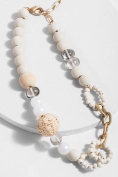 Our Beach Wooden Multi Beaded Necklace features an array of painted wooden beads that reflect the natural colors of the beach. Modernized with a gold-finished chain, this piece combines rustic with contemporary. Size: 17" x 0.8" Lobster Clasp with 3.5" extender Imported Bohemian Chain Necklace For Vacation, White Chain Necklace For The Beach, White Chain Necklace For Beach, Beaded Necklaces For Vacation, Natural Beaded Necklaces For Vacation, Beach Necklaces With Round Beads Chain, White Wooden Beads Jewelry For The Beach, Wooden Bead Necklaces For Vacation, White Wooden Beaded Necklaces For Beach