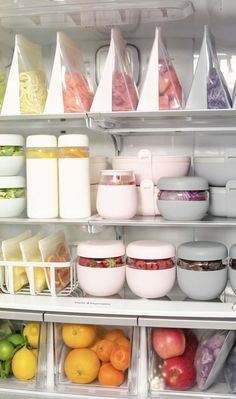 an open refrigerator filled with lots of food and containers full of fruit, vegetables, and other items