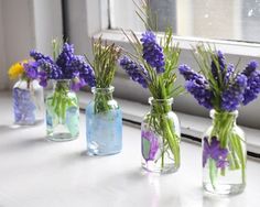 four vases with flowers in them sitting on a window sill