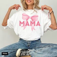 a woman sitting on top of a wooden table wearing a white shirt with pink bow