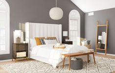 a large white bed sitting in a bedroom next to a wooden table and lamp fixture