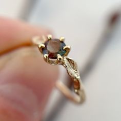 a close up of a person's hand holding a ring with a stone in it