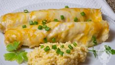 two enchiladas on a plate with rice and green onions