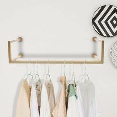 some clothes hanging on a rack in front of a white wall and a black and white circular object