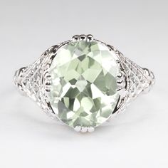 This vintage style ring features a prasiolite (green amethyst) set in a sterling silver setting. The Art Deco style setting is beautifully crafted with lattice-like filigree. The prasiolite is a natural, earth mined stone. The ring measures 13mm across (north south) and 7mm from finger to top. Please note that colors can vary slightly depending on your monitor and display settings. An appraisal is available upon request. All of our pieces come with a 30 day return policy and 100% satisfaction gu Amethyst Set, Vintage Style Rings, Amethyst Color, Ring Art Deco, North South, Green Amethyst, Natural Earth, Eternity Bands, Deco Style