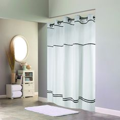 a white shower curtain with black trim in a bathroom next to a mirror and rug