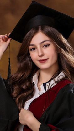 a young woman wearing a graduation cap and gown posing for a photo in front of a brown background