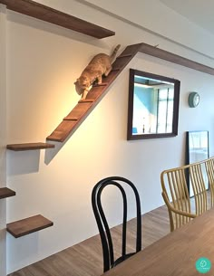 there is a cat sitting on top of the stairs in this dining room table and chairs