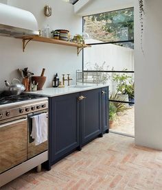 a kitchen with an oven, dishwasher and shelves on the wall above it