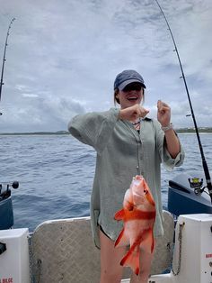 a woman on a boat holding up a fish