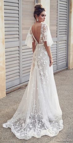 a woman in a white wedding dress standing on the street with her back to the camera