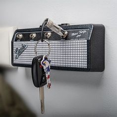 a wall mounted guitar amplifier with keys hanging from it's hooks and keychains