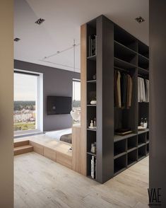 an open closet in the middle of a room with wooden flooring and large windows