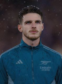 a soccer player is standing in the rain with his head turned to look like he's wearing a blue jacket