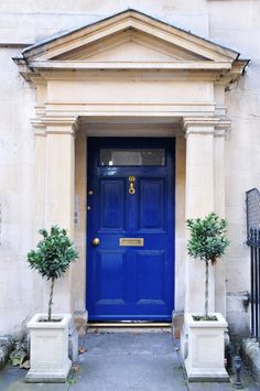 a blue door with two planters in front of it