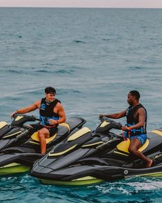 two men sitting on jet skis in the ocean