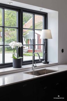 a kitchen with a sink, window and lamp on the counter top in front of it