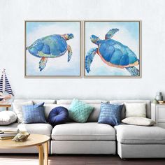 two paintings of sea turtles are hanging on the wall above a couch in a living room