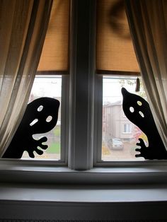 the window is open and there are two black cats looking out at the street outside