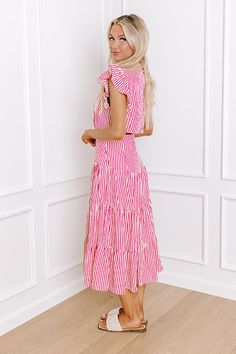 - Stroll through the farmer's market in this darling dress! - Lightweight material with a stripe pattern - A v-cut neckline - Short flutter sleeves - Pleated detail - A low cutout detail - A built-in skirt lining - Hidden side pockets - A flowy yet flattering silhouette that ends in a maxi length hemline Pink Vertical Stripe Summer Dress, Pink Vertical Striped Summer Dress, Striped Dress With Ruffle Sleeves For Spring, Striped Vacation Dress With Smocked Back, Striped Dress With Smocked Back For Vacation, Skirt Lining, Darling Dress, Farmer's Market, V Cut