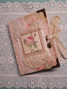 an altered book with lace and flowers on it