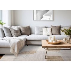 a living room with a couch, coffee table and vases on the floor in front of it