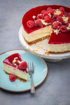 a cheesecake with raspberries and nuts is on a plate next to a fork