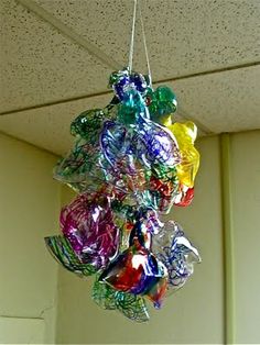 a bunch of colorful glass balls hanging from a ceiling in a room with white walls