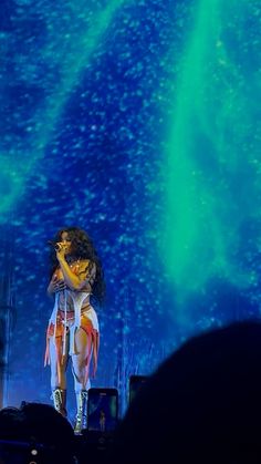 a woman standing on top of a stage with her arms around her head and hands behind her back