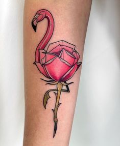 a flamingo tattoo on the leg of a woman with a rose in front of it