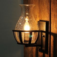 a light that is on the side of a wooden wall next to a glass vase