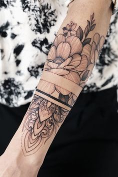 a woman's arm with a flower and ribbon tattoo on her left arm,