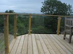 there is a wooden deck with railings on the top and trees in the background