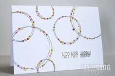 a white card with colorful beads and the words happy hip hurra written on it