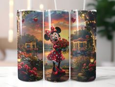 three mickey mouse travel mugs sitting on top of a white table next to each other