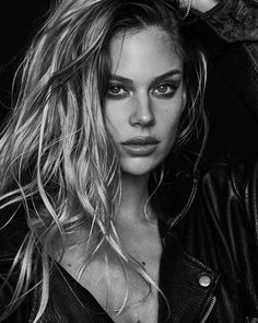 a woman with long hair and piercings posing for a black and white photo wearing a leather jacket