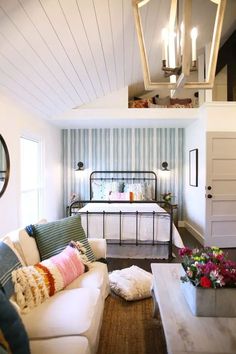 a living room filled with furniture and a white couch next to a bed on top of a hard wood floor