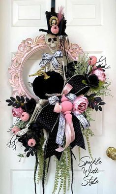 a wreath is hanging on the front door with pink roses and black ribbon around it