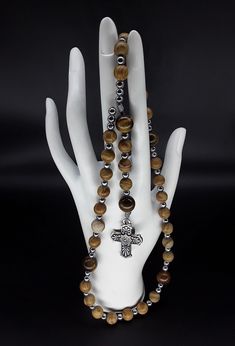 "The Anglican Rosary called \"our Holy Father\" is a beautiful rosary that is based on the heavenly golden colors which radiate a soothing effect while praying. The rosary is made of Jasper, Tigers Eye and Hematite gemstones (which have been cleansed and purified), Stainless Silver Cross with Saint Benedict medal. Finally, the rosary has been blessed by the church. Rosary: Anglican configuration Blessed: Yes About the Rosary: The Rosary has a Cross, an Invitatory bead, 4 sets of 7 beads that are Spiritual Rosary With Natural Stones As Gift, Spiritual Hematite Round Bead Jewelry, Spiritual Handmade Hematite Jewelry, Spiritual Hematite Jewelry With Polished Beads, Spiritual Brown Rosary For Healing, Brown Hand-strung Rosary As Gift, Brown Hematite Jewelry Gift, Spiritual Rosary With Polished Beads For Healing, Spiritual Hematite Jewelry For Gifts