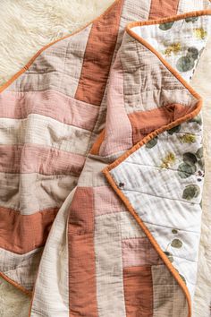 an orange and white blanket laying on top of a rug