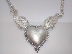 Please note, we also have for sale the matching earrings to this necklace in our Etsy shop! An absolute superb quality and beautifully designed piece of jewellery. The pendant is a heavily cast sterling silver heart set between two wings all of which have a frosted type finish to them. The chain is attached at the tip of each wing. Perfect condition  Fully hallmarked for sterling silver The pendant is 6.5cm across the tips of the wings. The necklace is 44cm long and 0.5cm wide Silver Hallmarked Double Heart Jewelry, Silver Double Heart Hallmarked Jewelry, Silver Angel Wings Pendant Necklace, Sterling Silver Heart Jewelry With Angel Wings, Elegant Wing-shaped Silver Jewelry, Elegant Silver Wing-shaped Jewelry, Silver Heart Wedding Necklace, Sterling Silver Angel Wings Jewelry For Anniversary, Elegant Heart-shaped Angel Wings Necklace