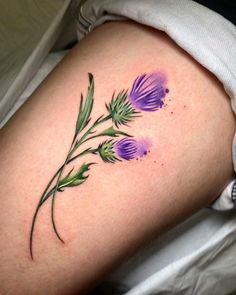 a woman's thigh with purple flowers painted on it and green leaves in the middle