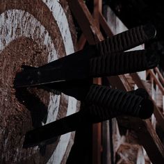 two black handles on an old wooden target in the dark, with only one arrow sticking out of it