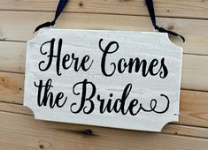 there is a sign that says here comes the bride hanging on a wooden plank wall