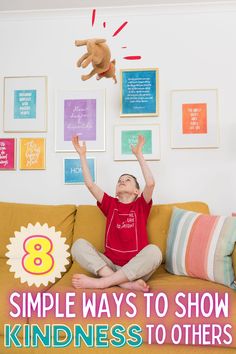 a little boy sitting on top of a couch with his arms in the air